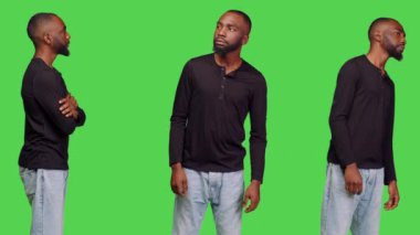 Stüdyoda yeşil ekranda poz veren rahat, arkadaş canlısı ve iyimser biri. Kot pantolonlu ve gömlekli bir genç stüdyoda pozitif, sıradan bir model..