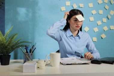 Ofiste masa başında oturan Asyalı iş kadınının kafasını kaşıdığından kuşkuluyum. İş yerinde alnında soru işaretiyle oturan belirsiz bir şirket çalışanı..
