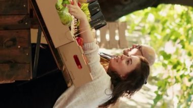 Dikey video: Çeşitli çiftçiler, sokak fuarından ev yapımı taze biyolojik ürünler almak isteyen satıcılarla pazar tezgahını ziyaret ediyorlar. Erkek ve kadın, yeşil marketten organik sebze alıyor..