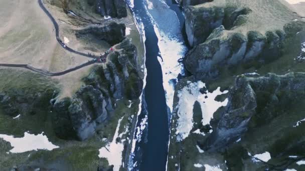 水の流れと美しい風景を形成する雪の山とアイスランドの峡谷のドローンショット アイスランドの川 自然の北極の景色を持つ壮大なフィヨルドのような峡谷 スローモーション — ストック動画