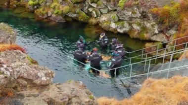 Thingvellir Ulusal Parkı, İzlanda - 3 Mart 2023 - Şnorkelle yüzme sporu, insanların doğa yüzüşünde eğlenmesi. Soğuk suda. Turistler dondurucu soğuk suya dalıyor