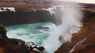 İzlanda 'da Gullfoss şelalesi muhteşem su akıntısı ve vahşi Reykjavik manzarasıyla. Karlı uçurumların kenarından akan nehir taşması, İskandinav manzaraları. El kamerasıyla..