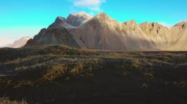 Stoksnes sahilinde kayalık dağlar, İzlanda 'daki doğal siyah kumsalın yanındaki görkemli vestrahorn dağları. İzlanda manzarasının panoramik görüntüsü ve işaretleri, manzaralı rota.