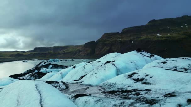 雪の山の周りに大規模なクレバスとアイスランド 美しい氷のブロックでVatnajokull氷河のキャップのドローンショット 凍った湖に浮かぶ雄大な霜の氷山 スローモーション — ストック動画