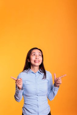 Mutlu Filipinli kadın sarı arka planda poz veriyor. Kendine güvenen esmer genç yetişkin reklam ürünü, reklam simgesi veya kamera önünde örnek gösteriliyor.