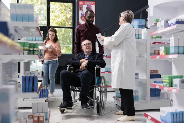 Pečovatel Pomáhá Staršímu Zákazníkovi Invalidním Vozíku Nakupováním Zdravotní Péče Lékárně — Stock fotografie