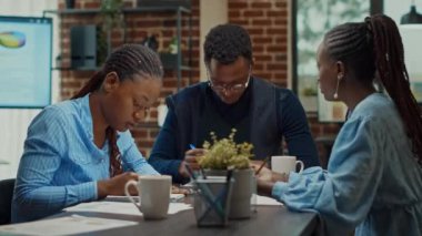 Yıllık belge ve bilgisayar raporlarını analiz eden bir grup insan, iş yerindeki çevrimiçi analizleri kontrol ediyor. Girişim ekibi kalkınma stratejisi ve kar artışı hakkında tartışıyor.