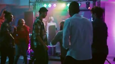 Mutlu yetişkinler kulüp partisinde doğaçlama dans dövüşü yapar, dans pistinde disko müziği ve spot ışıklarıyla zıplarlar. Gece kulübünde havalı hareketler sergileyen bir grup insan. El kamerasıyla..