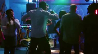 Kutlamada dans eden gülümseyen insanlar modern müzik dinliyorlar, dans pistinde parti yapıyorlar. Farklı yetişkinler DJ 'lerle ve sahne ışıklarıyla eğleniyor. El kamerasıyla..