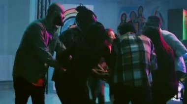 Çeşitli insanlar kulüpte eğleniyor, renkli ışıklar eşliğinde canlı müzik performanslarında dans ediyorlar. Disko partisinden ve sosyal toplantıdan hoşlanan genç erkekler ve kadınlar. El kamerasıyla..