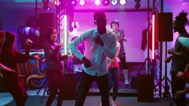 快乐的男人和俱乐部里的人一起跳舞 在迪斯科舞厅里享受着时髦凉爽的音乐 年轻人在舞池里聚会和跳来跳去 在酒吧里聚会 手持射击 — 图库视频影像