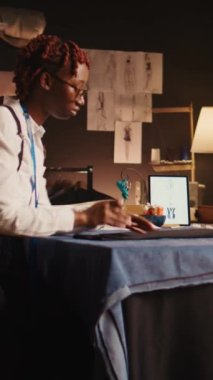 Dikey video Afrikalı Amerikalı terzi atölyede özel yapım tasarımlar için el yapımı araçlar ve malzemelerle çalışarak özel dikey takım elbise yapmak için kumaş hazırlıyor. Genç terzi el yapımı.