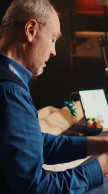 Dikey video stresli terzi atölyede lüks giyim markası tasarlamaya çalışırken çizimler çiziyor. Profesyonel modacı ve işyeri sahibi yeni kıyafetler yaratmak için baskı altında çalışıyor. El bilgisayarı