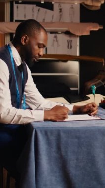 Dikey video uzmanı elbise çizimi yapıyor, lüks atölyede moda ürünleri tasarımı için vizyon yaratıyor. Profesyonel zanaatkar işyeri sahibi giysi ve el yapımı tasarımlar üzerinde çalışıyor..