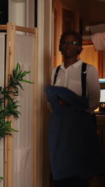 Dikey video terzileri moda tarzı dikiş işlemleri için kumaş hazırlıyor, taslak üzerinde mükemmel bir model seçiyorlar. Elbise tasarımı üzerinde çalışan terzi ve asistan. El kamerasıyla..