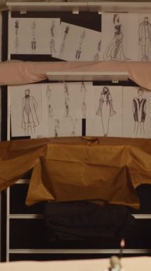 Dikey video lüks moda atölyesi, eskizler, dikiş aletleri ve atölyede özel yapım kıyafetler yapmak için kullanılan aletler. Dikiş dikmek için çizimleri ve kumaşı olan boş terzilik işleri.