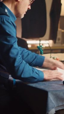 Dikey video sunucusu eşyalar ve dikiş aletleriyle eskizleri inceliyor, lüks atölyelerde kıyafet yapmaya çalışıyor. Tasarımlar yaratmak için kumaş ve çizimler kullanan profesyonel bir modacı..