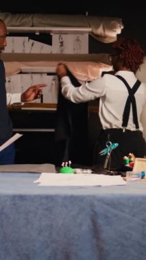 Atölyede dikey video alıcısı takım elbise ceketi, mükemmel uyumu sağlıyor. Üst düzey tasarımcı ve çalışan atölyede uygun ölçülerde lüks kıyafetler üretiyor. El kamerasıyla..