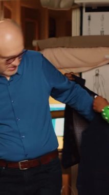 Dikey video üst düzey müşterisi terzilik atölyesinde takım elbise denerken, terziler özel dikim elbiseler tasarlamadan önce uygun ölçüleri sağlama alıyor. Müşteri kıyafet siparişini kontrol ediyor
