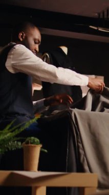 Dikey video Terzileri moda koleksiyonu için kumaş kalıpları hazırlıyor, çizimler için mükemmel tasarımı seçiyorlar. Tasarımcı ve asistan giyim markası üzerinde çalışıyor. Üçayak