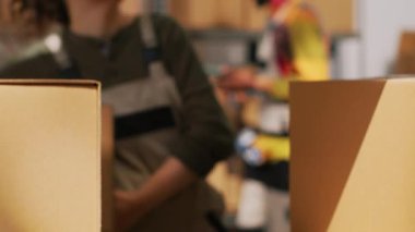 Kadın yönetici raflarda kutu taşıyor, depo deposunda mallarla çalışıyor. Ürünlerin ambalajlarını düzenleyen genç denetleyici, sipariş dağıtımını onaylıyor. El kamerasıyla. Kapat..