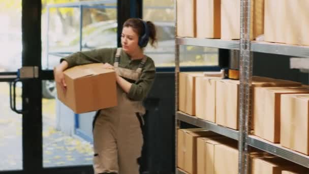 棚の箱を整理し 小売出荷のための注文を準備する前にパッケージを運ぶ監督者 貯蔵室の商品在庫を点検する若い大人の音楽を聞いている 手持ち撮影 — ストック動画