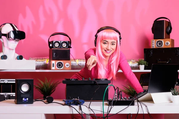 亚洲音乐家站在Dj桌旁 用专业的转盘 在众人面前表演音乐 将Techno歌曲与电子音乐混合在一起 粉红头发的表演者喜欢在夜店表演 — 图库照片
