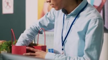Modern butikte alışveriş sırasında ödeme terminalini kullanarak şık kıyafetlerin parasını kredi kartıyla ödeyen Afrikalı Amerikalı bir kadın. Müşteri giyim mağazasından resmi kıyafet alıyor. Moda konsepti