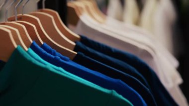 Askıların ve askıların seçici odak noktası temel tişörtle dolu, modaya uygun kıyafetlerle dolu boş modern butik. Alışveriş merkezi yeni moda koleksiyonu müşterileri bekliyor..
