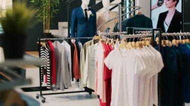 Raflarda modaya uygun giysiler, modaya uygun eşyalar ve giyim mağazasında resmi giysiler olan modern butiğin içi. Alışveriş merkezindeki boş galeri askılarda yeni moda koleksiyonu var.