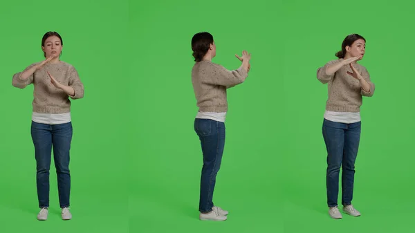 Full body of model doing t shape timout sign on green screen backdrop, showing break or pause symbol with arms. Woman standing over greenscreen with negative refusal symbol in studio.