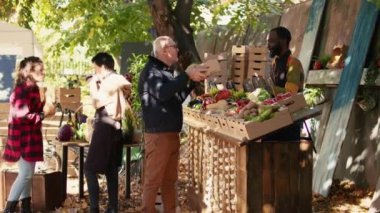 Afro-Amerikan satıcıdan organik ürün almak isteyen üst düzey bir müşteri sağlıklı beslenme ve yerel ürünlerden bahsediyor. Yaşlı adam marketten meyve ve sebze alıyor..