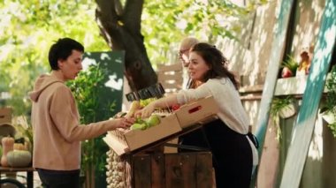 Tedarikçilerle çiftçi pazarını ziyaret eden çeşitli çiftler, sokak fuarından taze biyo ürünler almak istiyorlar. Erkek ve kadın, yeşil marketten organik sebze alıyor..