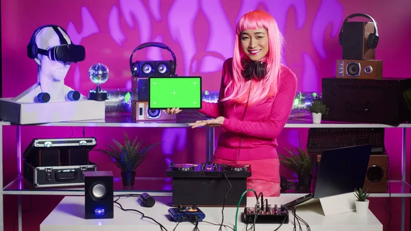 Dj与粉色头发持有绿色屏幕彩色键盘片与隔离显示 同时混合工艺声音和电子促销新的阿尔本夜总会 艺人在表演时使用混音器控制台 — 图库照片