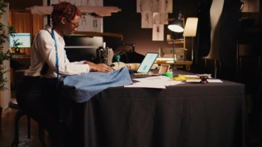 İş yerinde, profesyonel terzide giysi üretimi için dikiş makinesi üzerinde çalışan tasarımcı. Genç modacı atölyede özel yapım kıyafetler yapmak için terzilik ekipmanı kullanıyor..