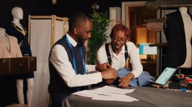 Tasarımcılardan oluşan bir ekip modern moda ürünleri yaratmak için terzilik ekipmanları seçiyor. İş ortakları kumaş ve araçlarla çalışan terziler, el yapımı kıyafetler tasarlıyorlar..