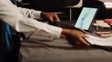 Modern kıyafetler yaratmak için terzi ve asistan kumaş seçiyor, atölyede moda koleksiyonu için kıyafet hazırlıyor. İki tasarımcı malzeme seçiyor, el yapımı. El kamerasıyla..
