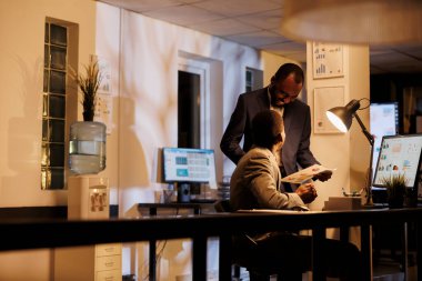 Şirket kârını artırmak için yatırım stratejisini tartışan finansal büyüme raporuna bakan girişimciler. Girişim ofisinde gece geç saatlerde yönetim projesinde çalışan şirket çalışanları