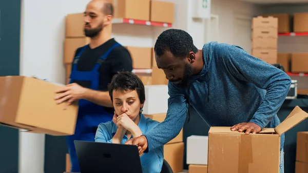 Business partners looking at stock and packaging, working on shipment and delivery. Man and woman checking quality of merchandise order at warehouse, retail wholesale supply chain.