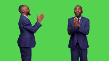 Olumlu iyimser bir yetişkin alkışlıyor ve alkışlıyor, yeşil perde arkasında poz veriyor. Genç işadamı destek veriyor ve tebrik ediyor, stüdyoda ayakta alkışlıyor..