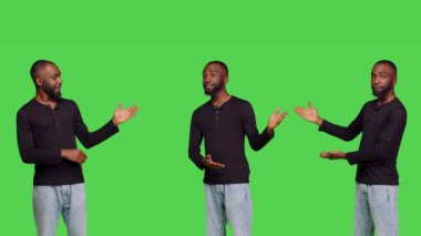 Sağ ya da sol tarafta reklamlar yapan rahat bir insan, yan tarafları işaret ederek kendine güveniyor. Genç yetişkin gelişigüzel yeşil ekran arkaplanı üzerinde reklam yapıyor..