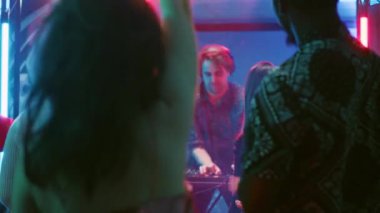 Kulüpte dans eden bir grup arkadaş, gece kulübü sahnesinde DJ ile canlı performans gösterisinin tadını çıkarıyorlar. Gençler dans pistinde disko ışıklarıyla parti yapıyorlar. Üçayak atışı.