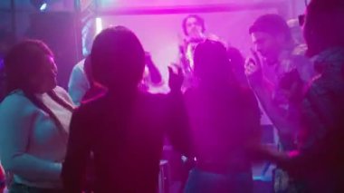 Havalı bir grup arkadaş partide eğleniyor, disko ışıkları altında eğleniyorlar. Gülümseyen insanlar dans edip dans pistinde zıplıyorlar, gece hayatı kutlama partisinin tadını çıkarıyorlar. El kamerasıyla..