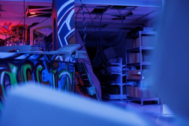 Terk edilmiş bir binada parlak neon ışıkların altında parlayan sanatsal çizimler, terk edilmiş eski karanlık uzayda duvarlara grafiti. Parçalanma durumunda floresan ışığıyla yok edilen depo..