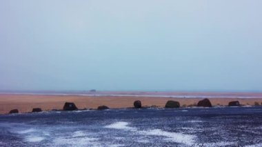 Rüzgârlı soğuk İzlanda manzarası, yol kenarı manzarası. Donmuş tarlalar ve arazi İzlanda 'da soğuk İskandinav manzarası yaratıyor, doğal manzara rotası. El kamerasıyla..