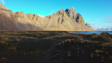 İzlanda 'daki güzel vestrahorn dağları ve tepeleri. Siyah kumlu plajları ve muhteşem İskandinav manzaraları var. Stoksnes plajı, panoramik manzaralı İzlanda doğası. El kamerasıyla..