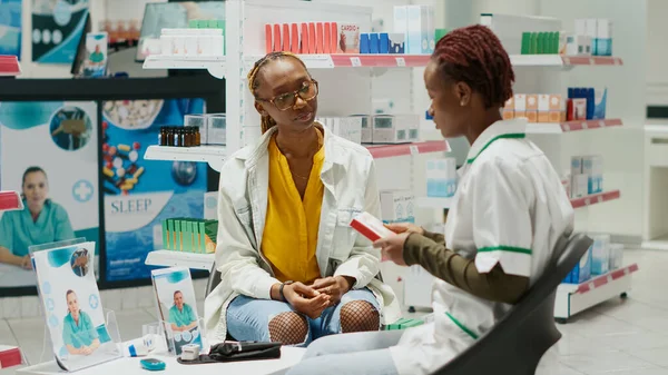 Female Pharmacist Showing Box Pills Young Client Giving Pharmaceutical Products — Stock fotografie