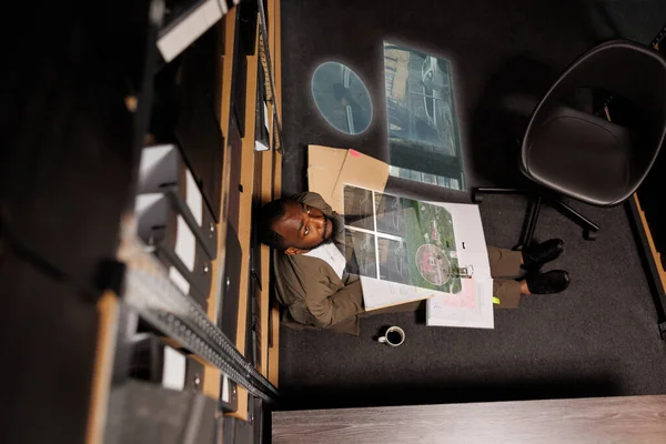 Private detective looking at case files and hologram, examining crime evidence and clues to catch suspect. Male investigator checking augmented reality technology, artificial intelligence.