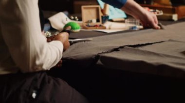 Öğrenci ve eski terzi atölyede el işi yapmak için malzeme kesiyor. Acemi dikiş dikmeden önce kumaş kesmek ve kıyafet tasarlamak için makas kullanıyor. Couturier ve çırağı. El kamerasıyla. Kapat..