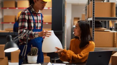Bir grup Asyalı depodaki ürünlere bakıyor, sevkiyattan önce ürünleri kontrol ediyorlar. Depo çalışanları dağıtım için kalite kontrolü üzerinde çalışıyorlar, küçük işletmeler. Üçayak atışı.